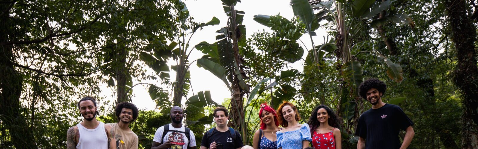 A diverse group posing happily together in a lush, outdoor setting.